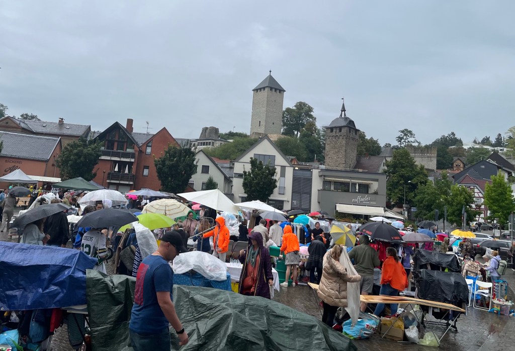 Menschen in Regenkleidung mit Regenschirmen beim
Flohmarkt auf dem Hofgartenplatz in Wiesbaden-Sonnenberg