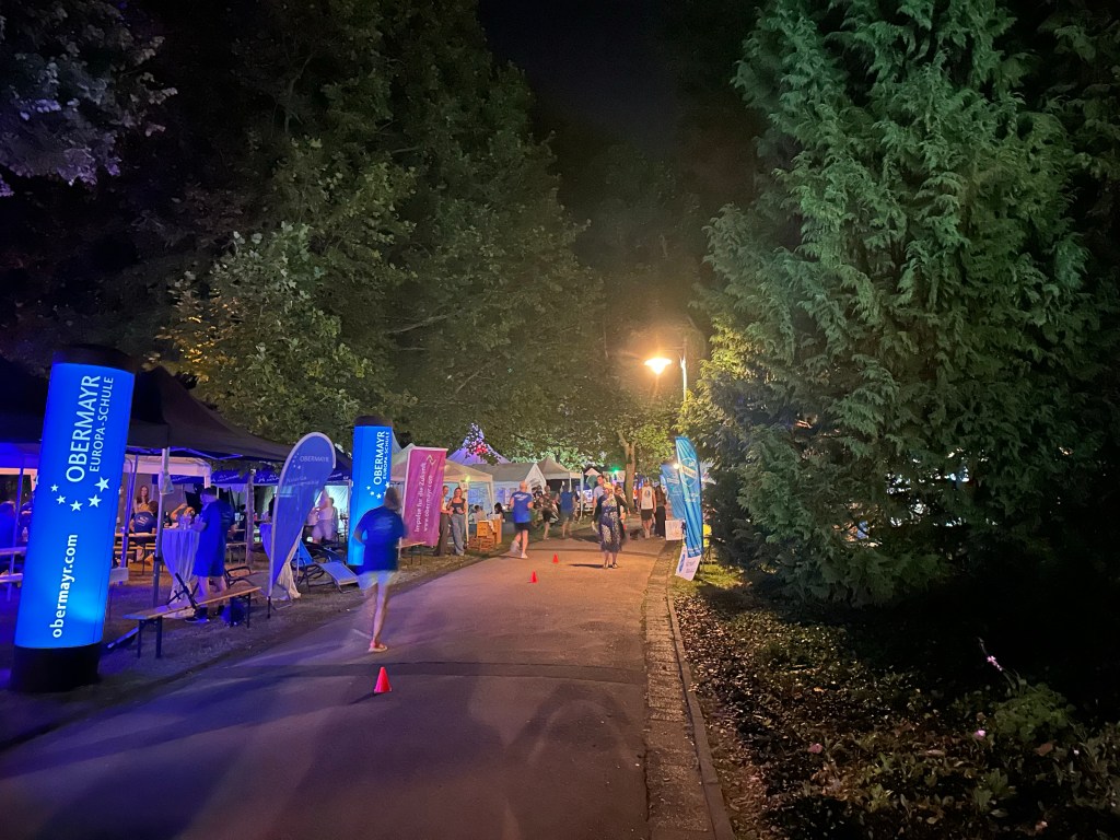 Nachtaufnahne vom bunt beleuchteten Kurpark, in dem Sportler Runden laufen